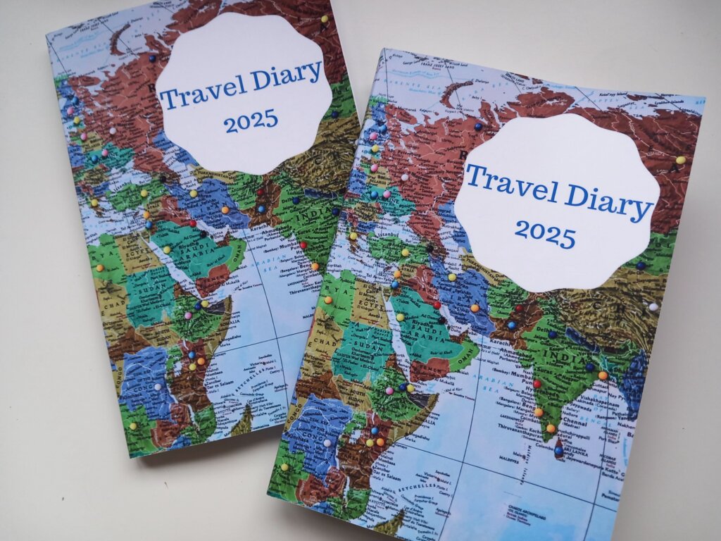 This image shows two copies of the 2025 travelk diary with world maps on the covers