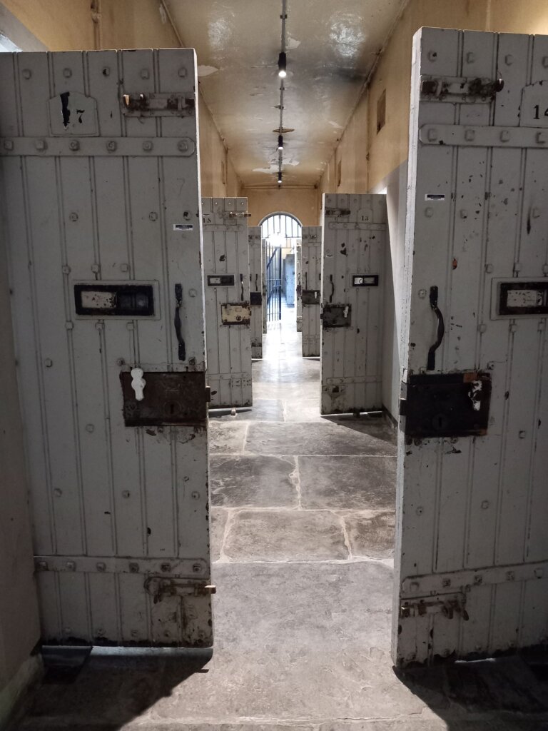 This photo shows several wooden doors to cells, all standing open to show the heavy locks