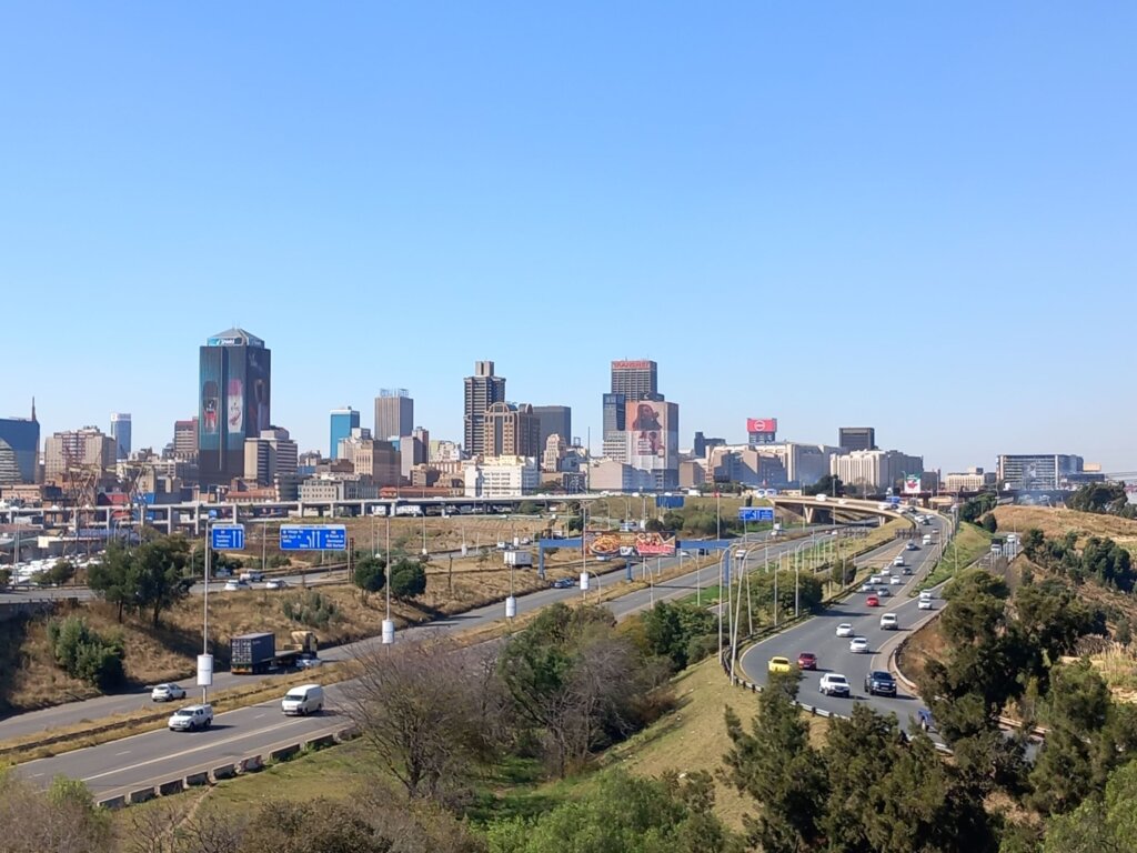 This photo, taken from the top of a City Sightseeing bus, shows the Johannesburg skyline with a major road and high-rise offices.