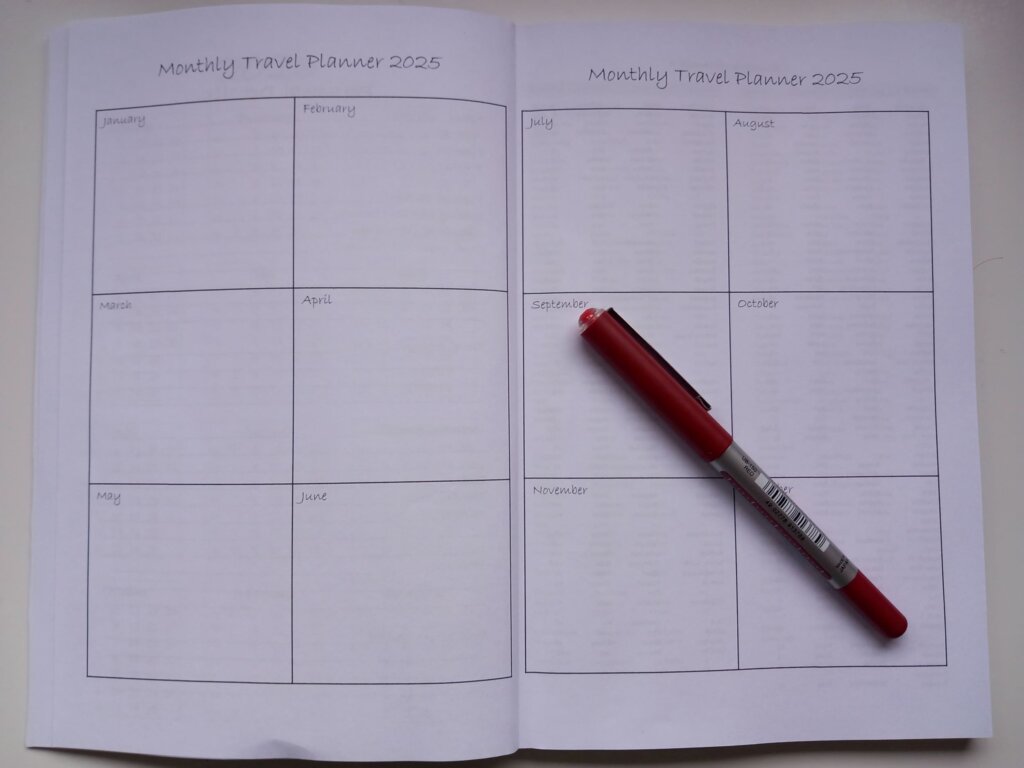 This photo shows the monthly planner page of the 2025 travel diary with a pen lying diagonally across it