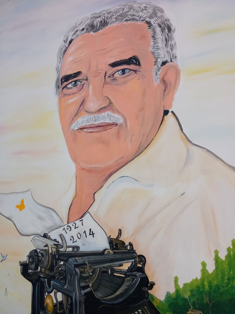 This image shows a mural of the author Marquez with a typewriter containing a piece of paper with the dates of his birth and death