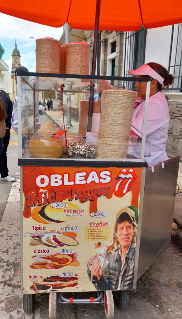 This image shows a street vendor's cart with Mick Jagger being used to advertise her obleas